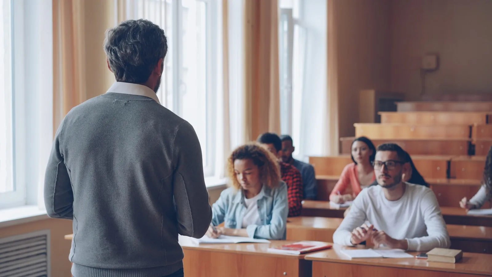 Professor with college students in a lecture hall — faculty assessing human-led research